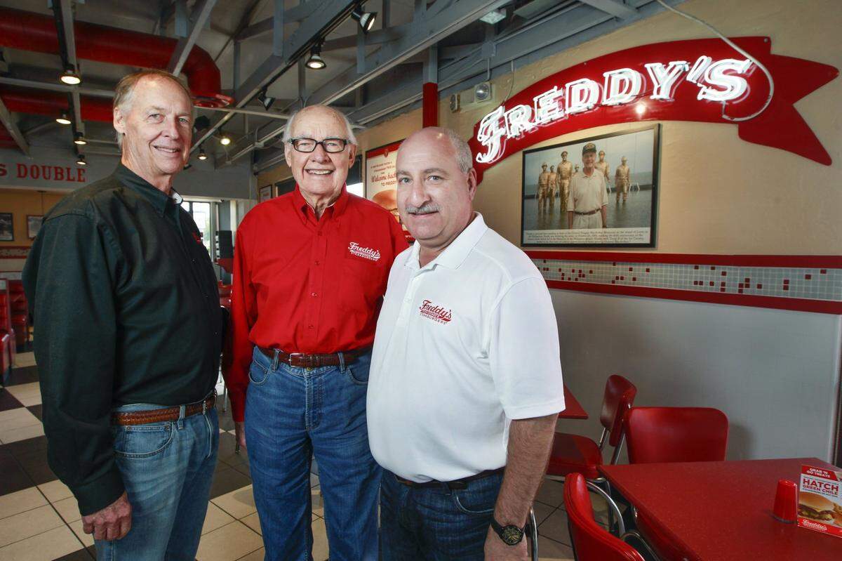 Freddy’s founders Randy Simon, left, and Scott Redler, right, pose with Freddy’s spokesperson Freddy Simon, center, during the chain’s 15th anniversary in 2017.