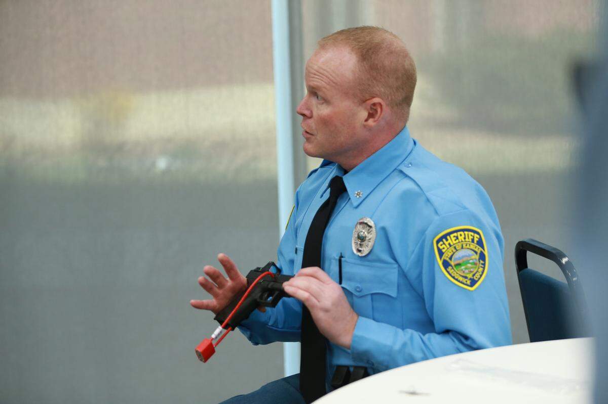 Sedgwick County Sheriff’s Office public information officer Branden Stitt demonstrates how to use a cable-style firearm lock.