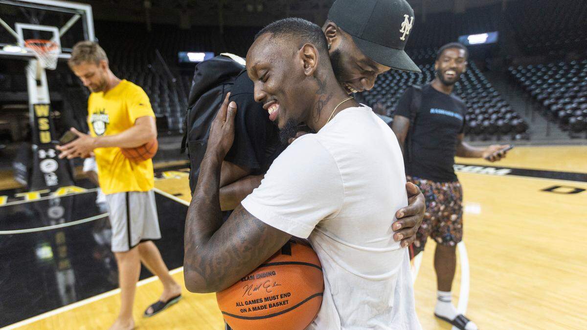 Former Wichita State basketball players Samajae Haynes-Jones and Markis McDuffie embrace on the Koch Arena court on Monday night. The two are are part of an all-star group of former Wichita State players, the AfterShocks, in town to compete in the TBT basketball tournament this weekend.