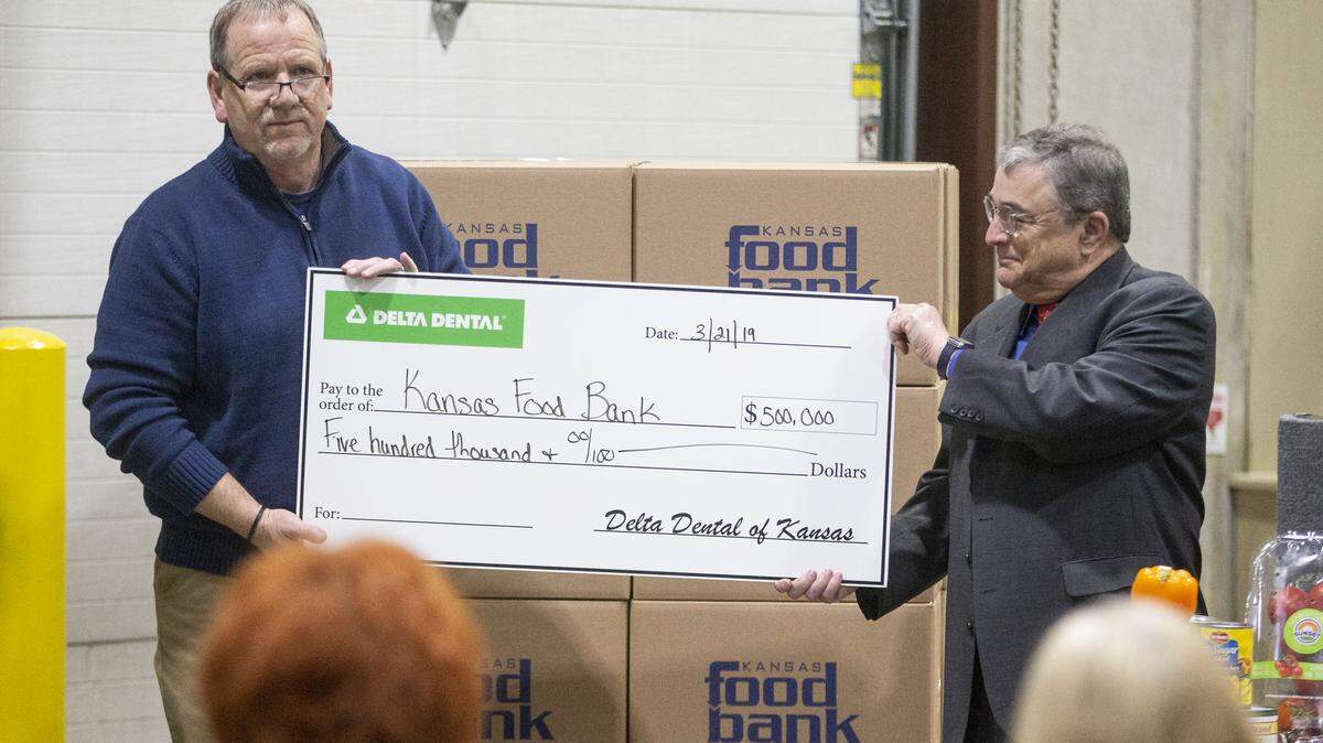 In this 2019 file photo, Brian Walker, left, president and CEO of the Kansas Food Bank, and Michael Herbert, president and CEO of Delta Dental of Kansas, hold up a check for $500,000. Delta Dental of Kansas donated the money to the Food Bank.
