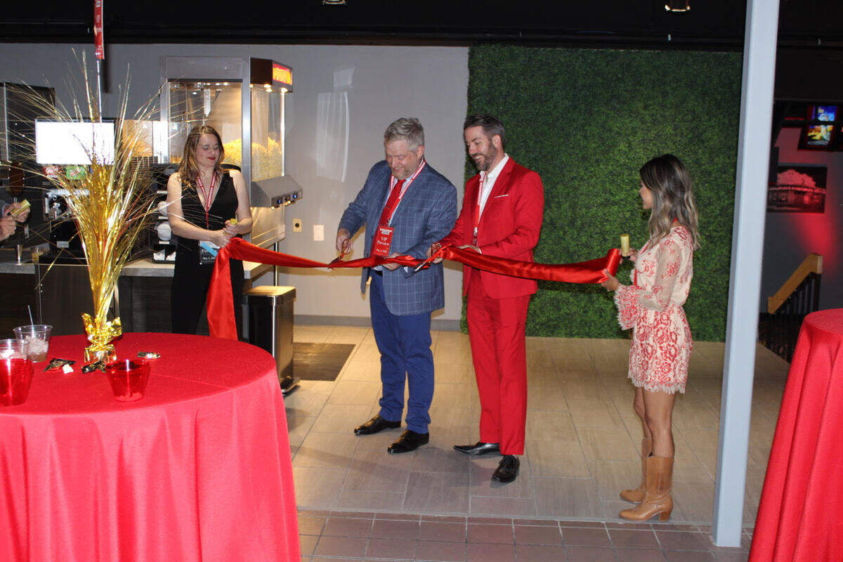 Towne West Square general manager Charley Cooper, left, and Felicia Blasdel hold a ribbon for their husbands, Tyler Cooper, in the blue suit, and Ryan Blasdel at a VIP night at their new Boulevard Theatres this week.