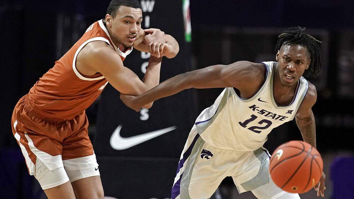 Texas forward Dylan Disu, left, and Kansas State forward Carlton Linguard Jr. (12) chase a loose ball during the first half of an NCAA college basketball game Tuesday, Jan. 4, 2022, in Manhattan, Kan. (AP Photo/Charlie Riedel)