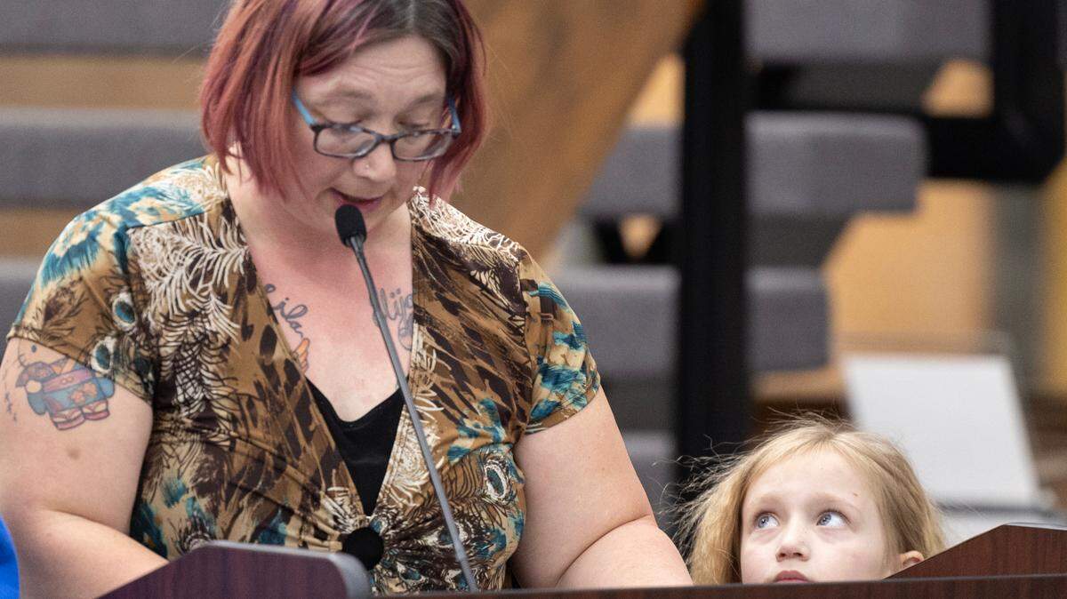 Jamie Petitjean addresses the Wichita school board at a public hearing on Thursday night while her daughter Lila listens. Lila Petitjean is a student at Clark Elementary, one of the schools that could close.