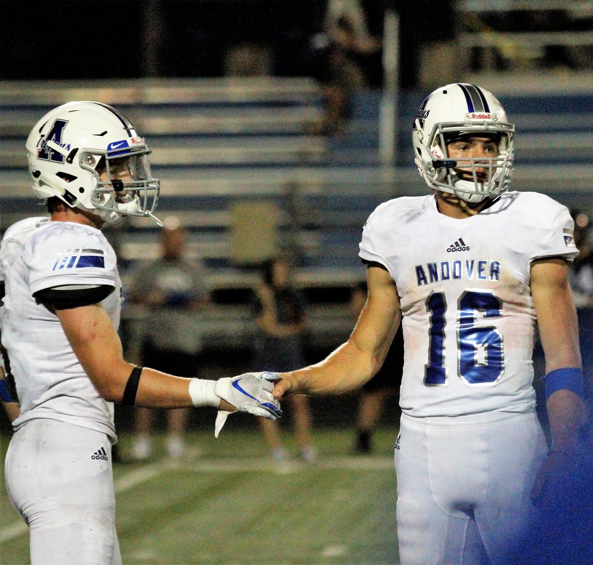 Andover quarterback Eli Fahnestock (16) and running back Peyton Henry (5) slap hands during the final seconds of the Trojans’ 30-22 win over Goddard Eisenhower on Thursday night. (Sept. 13, 2018)