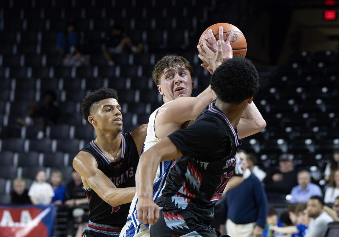 Kapaun’s Blaise Dalian looks for a pass while being swarmed by two Shawnee Heights defenders on Tuesday at the quarterfinals of the 6A basketball tournament at Koch Arena.
