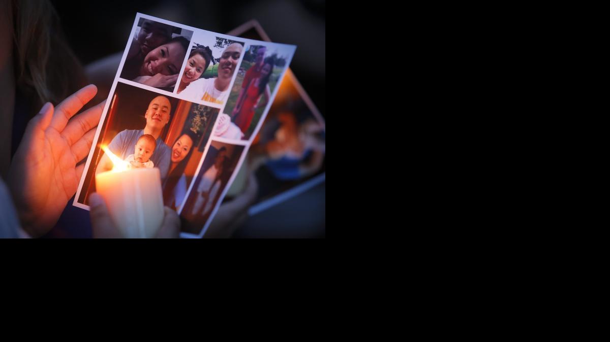 A candle is held next to a picture of Trinh Pham and Sean Pham during a vigil in front of the home in southeast Wichita where the young couple, along with Trinh Pham’s mother, Tuyet Huynh, were killed on June 24, 2014.