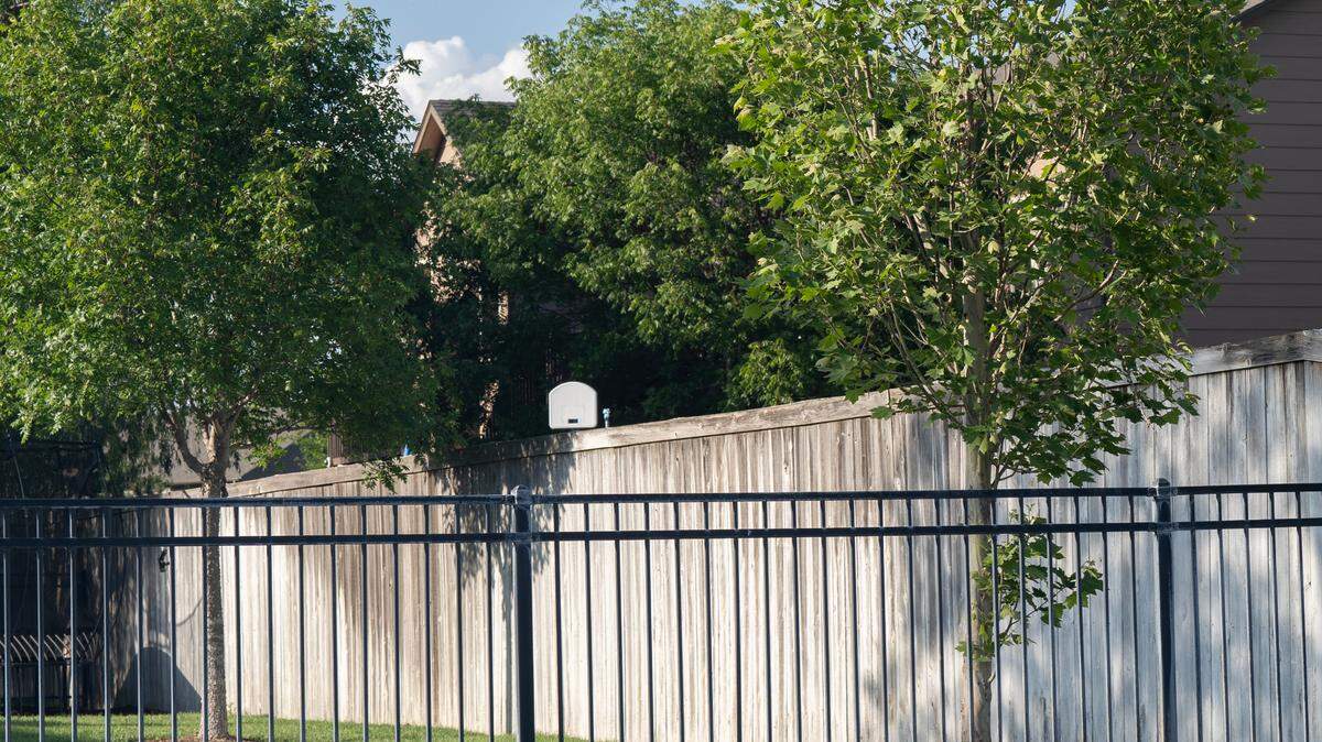 An eight-foot-tall wooden fence separates the The Hawthorne subdivision from the one next door.