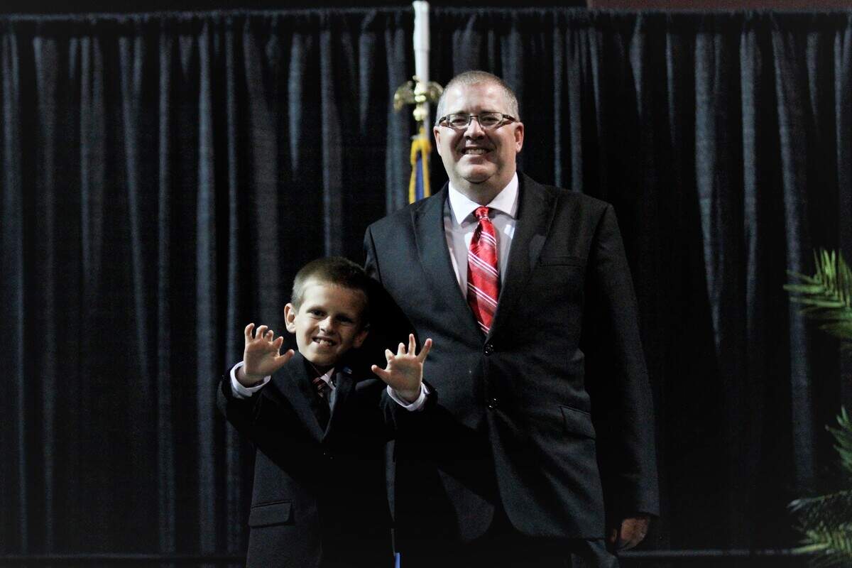 Jake and Eli Petersen stand on stage at the 2019 Shrine Bowl Player Appreciation Banquet in Dodge City as Eli shows his hands.
