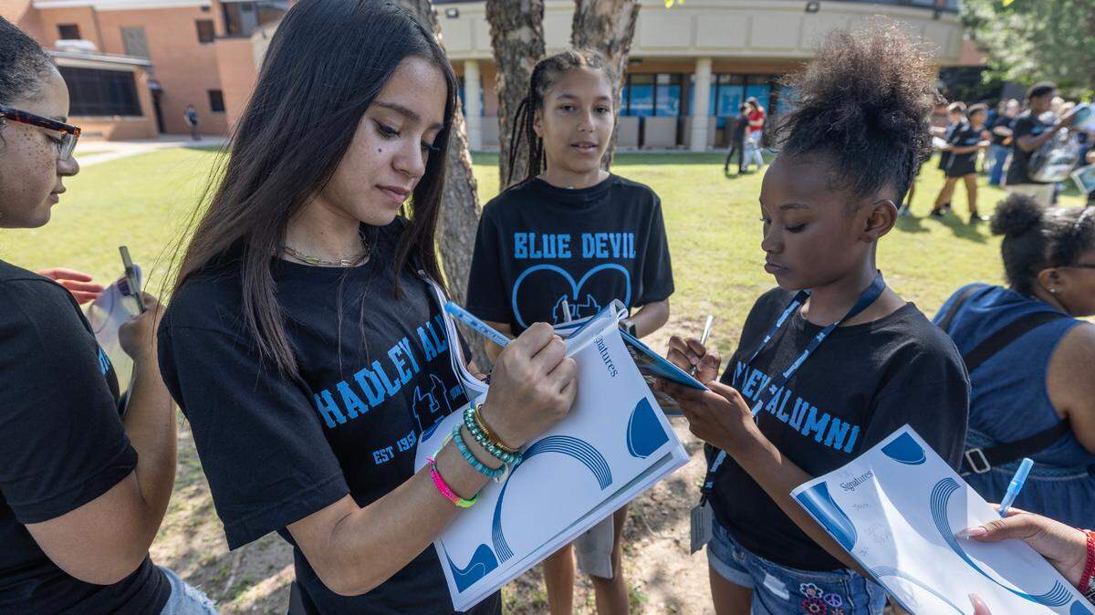 Hadley Middle School sixth-graders, from left, Remi Richardson, Jayden Gardiner-Roundtree and Melia Evans, sign one another’s yearbooks on the last day of school Thursday. Hadley was one of six schools that the Wichita school board voted in March to close, making Thursday the last and final day of school at the building.