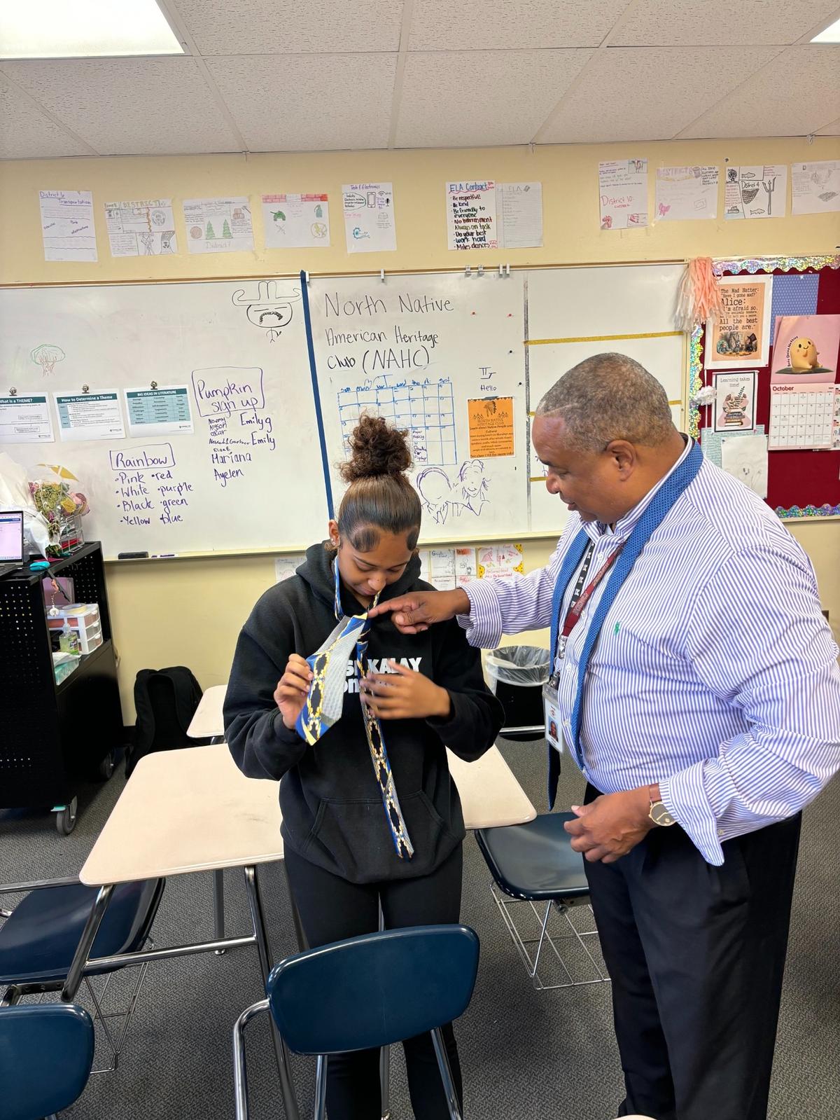 William Polite teaches a student how to tie a necktie inside a classroom.