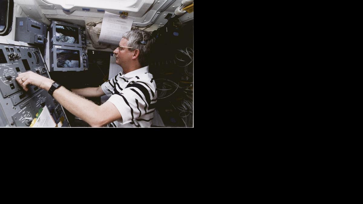 Astronaut and astronomer Steve Hawley, aboard the space shuttle, operates a robotic arm attached to the Hubble Space Telescope.


