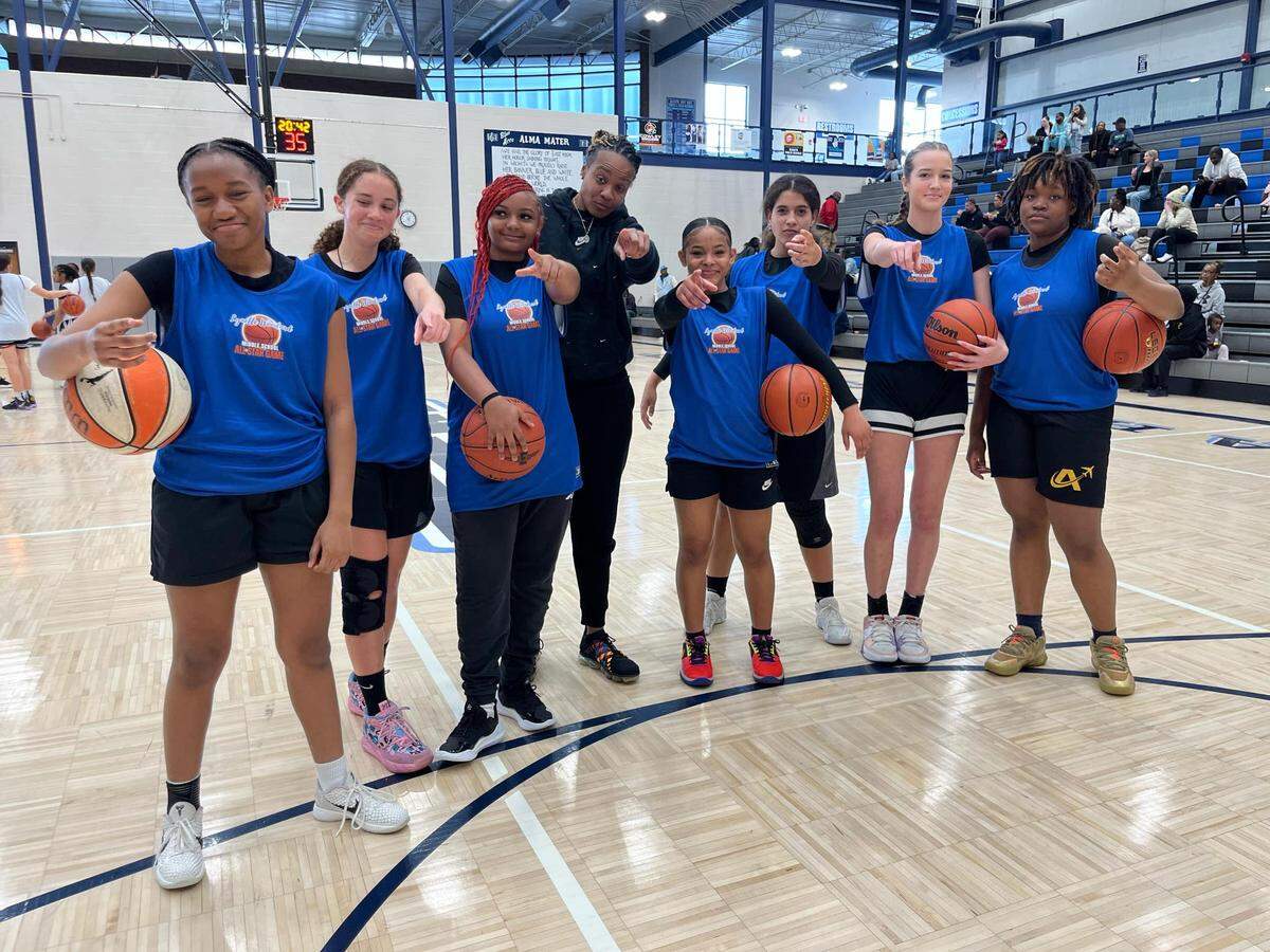 Players pose with coach Angela Buckner at the debut Lynette Woodard Middle School Basketball All-Star game this past weekend at East High.