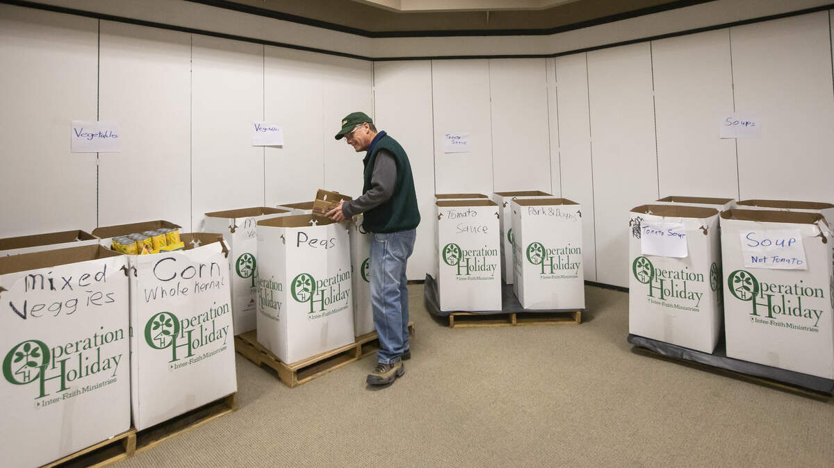 Chuck Graber sorts canned food items at the Operation Holiday headquarters at Towne West on Thursday. The organization says that their donations, especially food items, are down significantly this year.