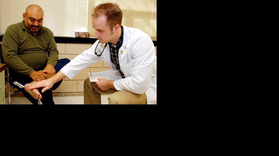 Austin Campbell, right, a first-year student at the University of Kansas Medical School-Wichita, checks the foot of Ruben Castillo during a visit to the Jaydoc Clinic at Guadalupe Clinic. To help with a physician shortage, administrators hope to expand the number of students who can complete four years of medical training in Wichita. 

