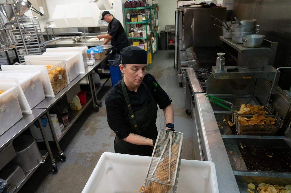 Deanna Stanley fries potato chips in the kitchen at INTRUST Bank Arena in preparation for the NCAA Basketball Tournament.
