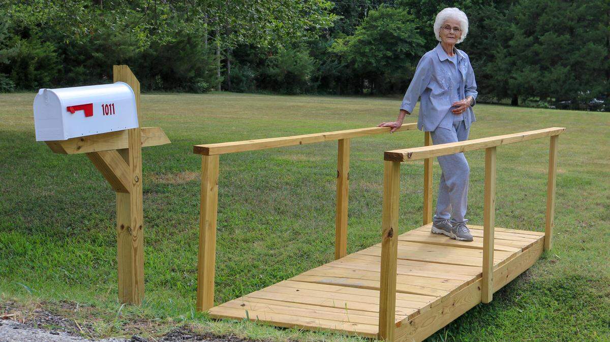 Joan Van Boening shows off the new bridge and mailbox Derby police officers built her after her old ones were destroyed in a hit-and-run crash.