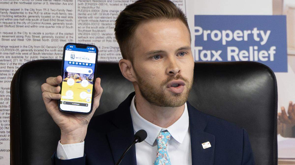 District 4 City Council member Dalton Glasscock holds up his phone showing the city of Wichita’s webpage while contending the city’s website should be the official newspaper of Wichita.