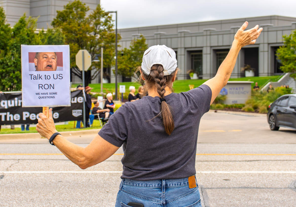 Nancy, a protester outside the Hyatt Regency Wichita, waves to passing cars while protesting U.S. Rep. Ron Estes' communication with his constituents. Estes spoke at the hotel during a federal issue forum on Aug. 28.
