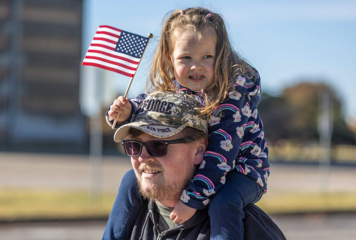 Shawn Levis, a nine-year Air Force veteran, watches the annual Veteran’s Day parade on Main Street in Wichita on Saturday while his daughter Madelyn, 3, perches atop his shoulders.