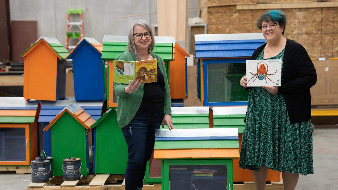 Jaime Nix, director of libraries for the Wichita Public Library, left, and Racine Zackula, the system’s family literacy coordinator, stand with free little libraries that will be placed throughout southeast Wichita.