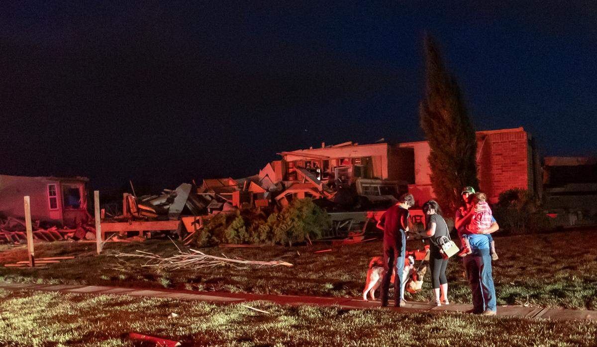 A family grabs a few items before evacuating on east Minneha Ave. in Andover on Friday night after a tornado ripped through the area.
