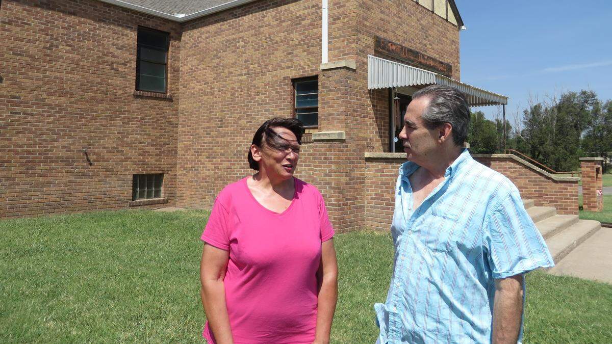 Dorothy Tobe and Mike Rosseau talk in the yard of the former church they bought, where the city of St. John has filed criminal charges to thwart their plan to live in it.