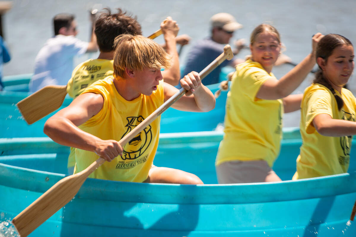 Prairie Schooner Mates, volunteers from Wichita-area high schools, race down the Arkansas River during the cowboy bathtub races on Saturday. The Schoonies focus on assisting this year’s Admiral Windwagon Smith, Lyle Schuette.