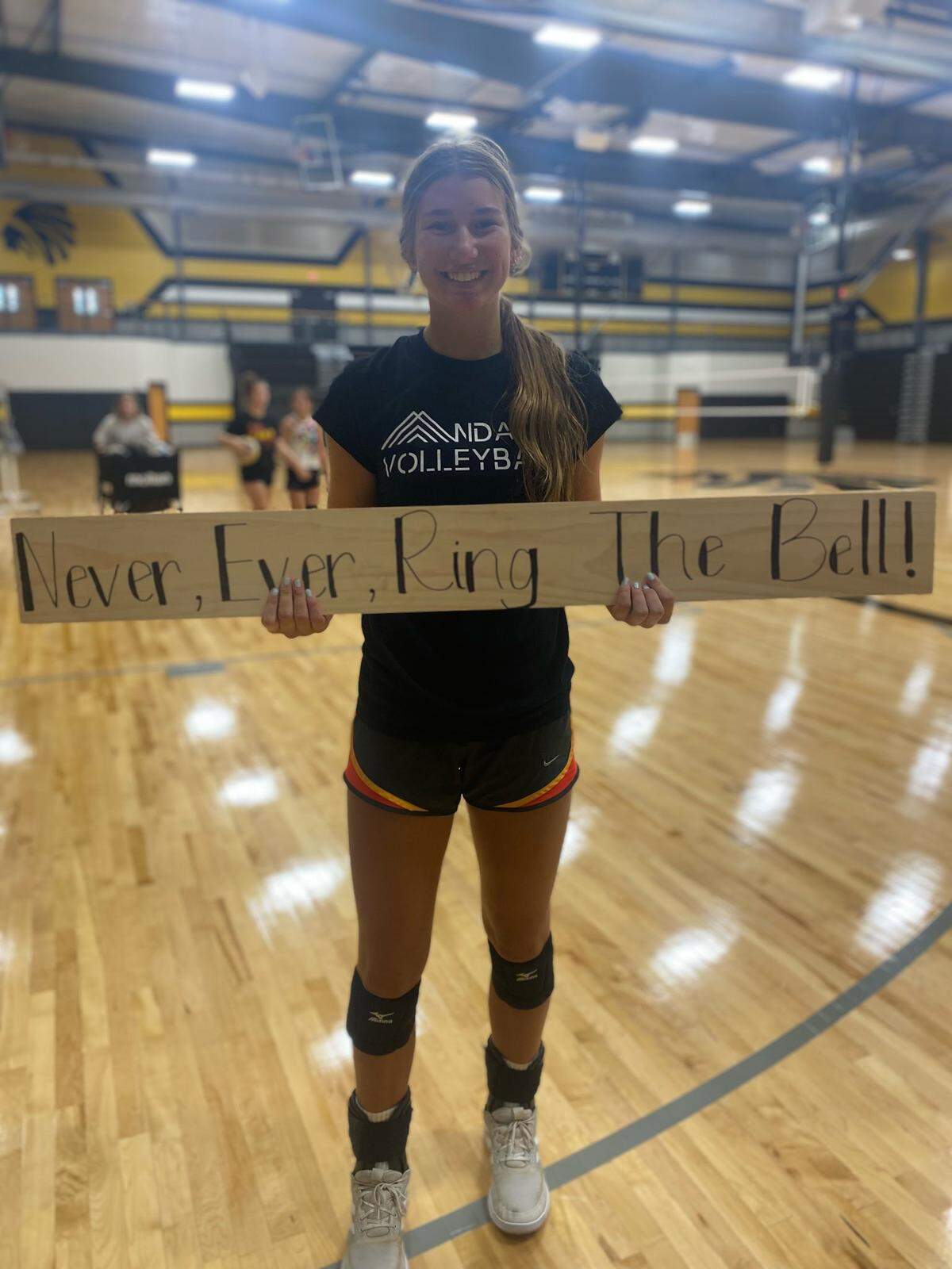 Andale junior Maddie Schrandt holds the wooden board with the team’s catch phrase “Never, ever, ring the bell!”
