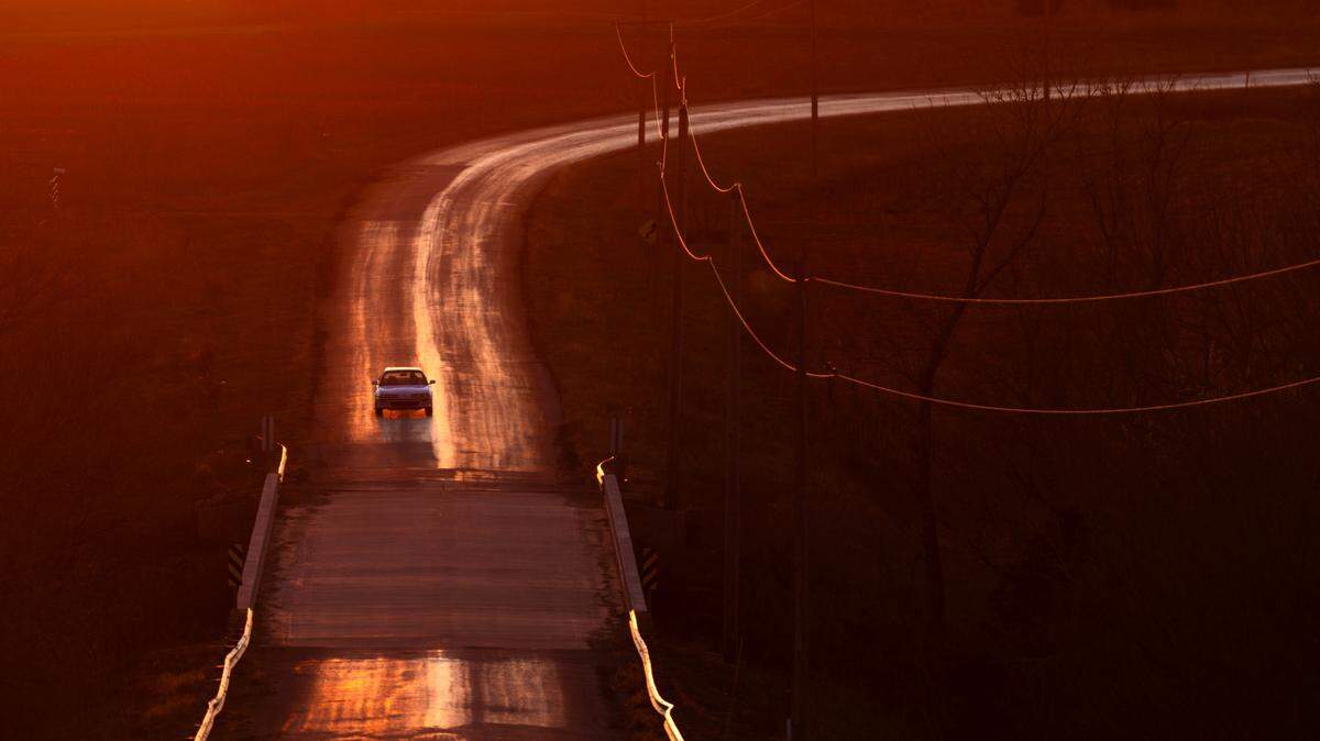 A car makes its way down a Chase County road between Elmdale and Cottonwood Falls at sunset.