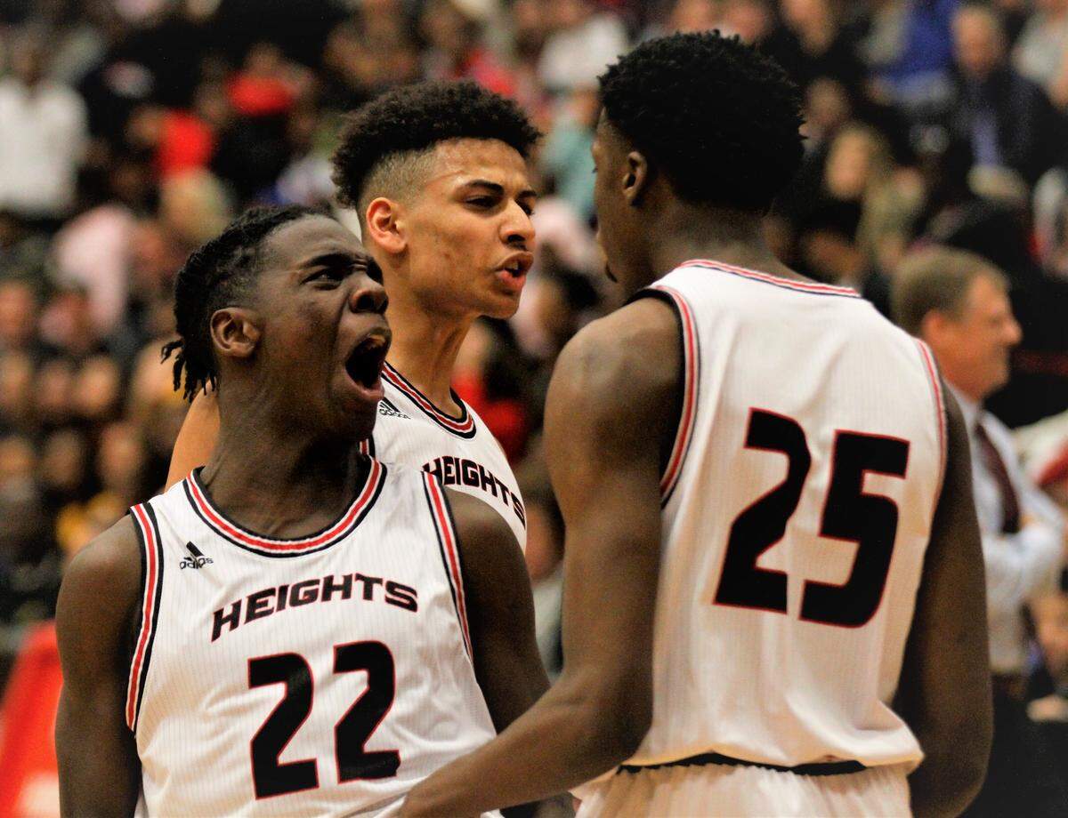 Wichita Heights’ Sam Kirugu (left) and Jaden Okon (center) celebrate with Danair Dempsey (right) during the Falcons’ home win over Wichita Southeast on Friday night. (Jan. 4, 2019)