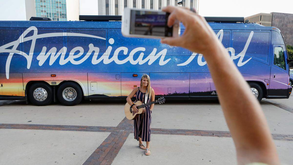 Makayla Brownlee has her photo taken in front of the American Idol bus outside of Century II on Wednesday morning. The popular television show was auditioning prospective contestants in Wichita.