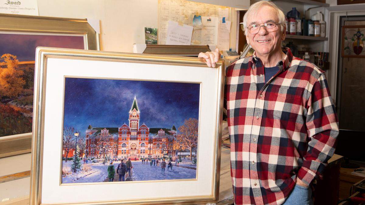 Wichita artist Hugh Greer with the most recent painting he made of Friends University for the Independent Living Resource Center holiday cards.
