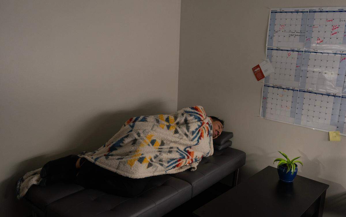 Salvador Hernandez, executive chef at INTRUST Bank Arena, demonstrates how he will sleep for a few hours over night during the NCAA Basketball Tournament. He predicts he will finish working at 1 a.m. on one of the days of the tournament and then start back up at 5 a.m. so he bought a fold-out sofa for his office to get a few hours of sleep.