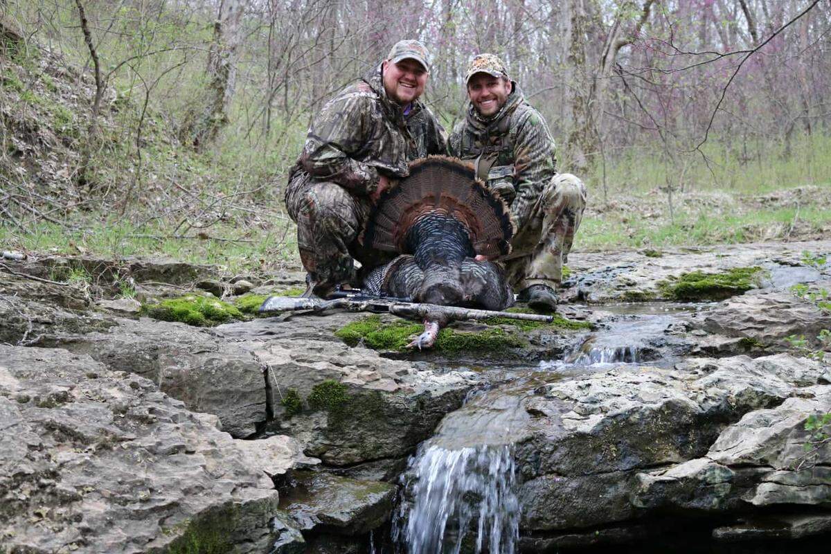 William Murphy, a legally blind Kansas veteran, poses for a photo with his turkey and guide, David Williams, who helps him pick up the turkey on a screen so he can shoot it.