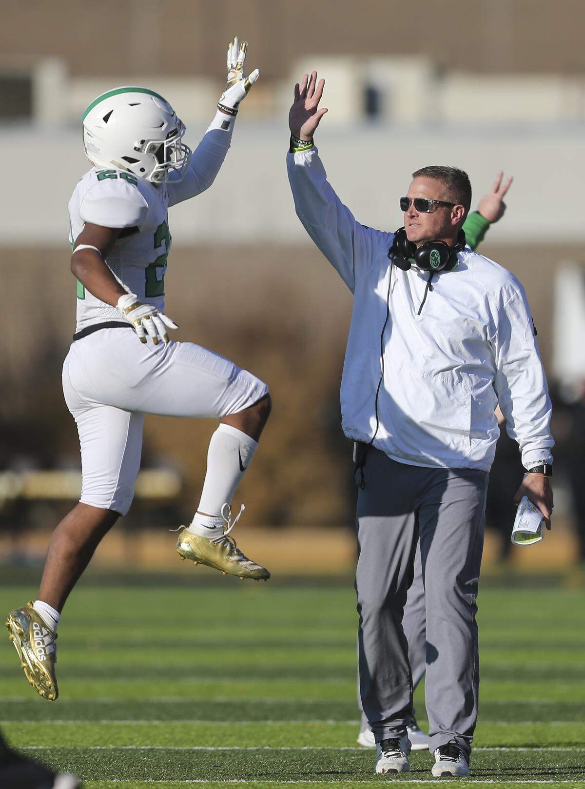Derby coach Brandon Clark congratulates senior Tre Washington after he made a big play in the 4th quarter against Olathe North.