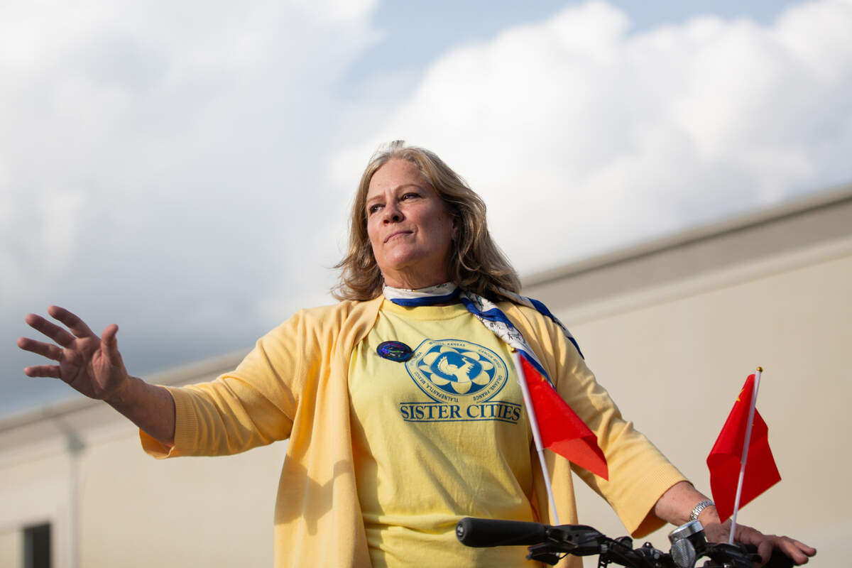 Celeste Racette, a member of the Wichita chapter of Sister Cities, rides down Main on a bike during the start of the the Riverfest Sundown Parade on Friday.