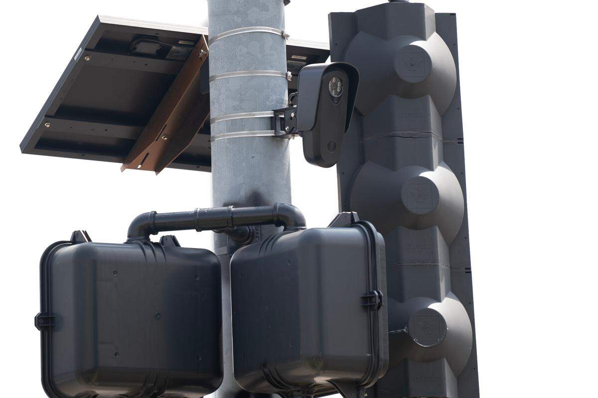 A Flock Safety device hangs from a light pole at the intersection of 13th and Grove where police are testing the company’s gunshot sensors. Police have been using the company’s license plate readers for several years but recently announced they would purchase the company’s gunshot sensors as well.