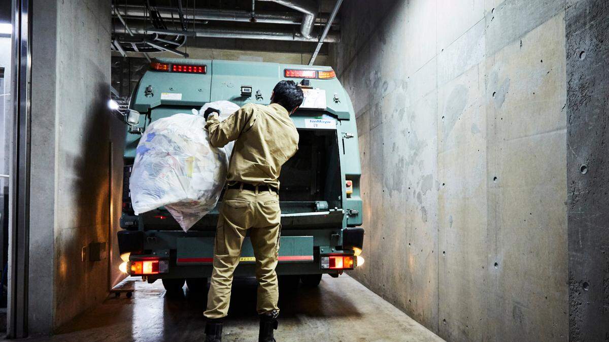 Garbage truck driver puts the collected garbage in the car.