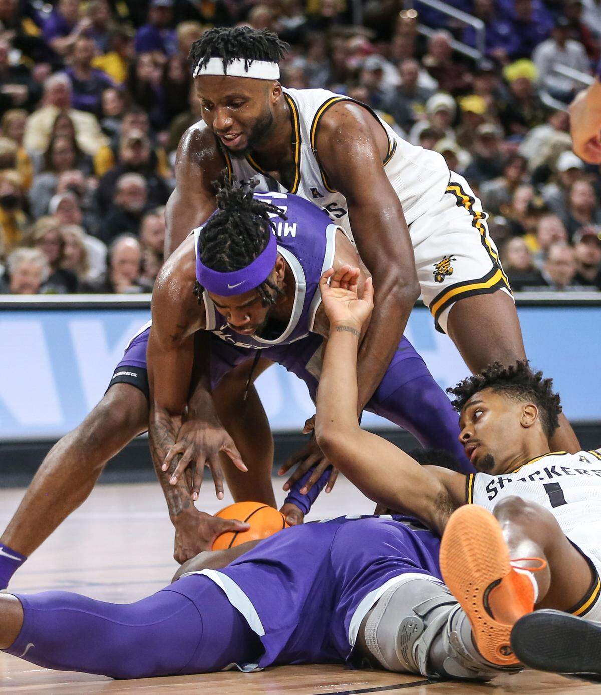Wichita State’s Morris Udeze, top, reachers over Kansas State’s Selton Miguel to get to a loose ball while Wichita State’s Tyson Etienne, bottom, right, tries to get in on the play during the second half on Sunday.
