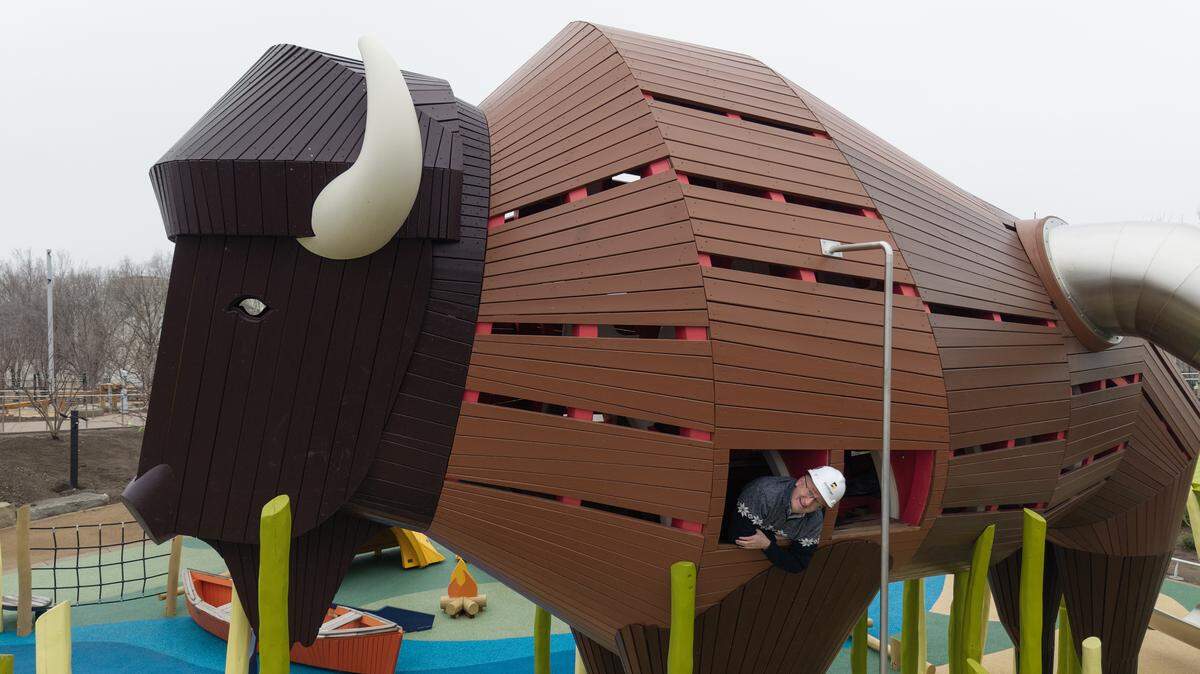 Exploration Place president and CEO Adam Smith pokes his head out of the 20-foot bison that’s part of the museum’s new $25 million Adventure Playscape.