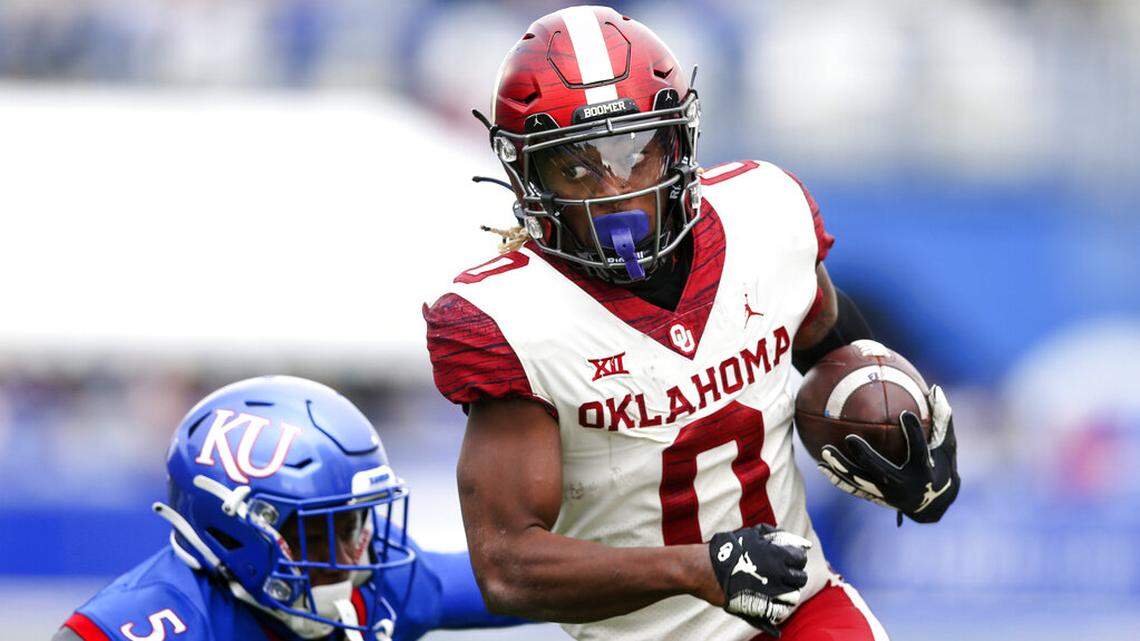 Oklahoma running back Eric Gray (0) runs past Kansas safety O.J. Burroughs (5) during an NCAA college football game, Saturday, Oct. 23, 2021, in Lawrence, Kan. (Ian Maule/Tulsa World via AP)