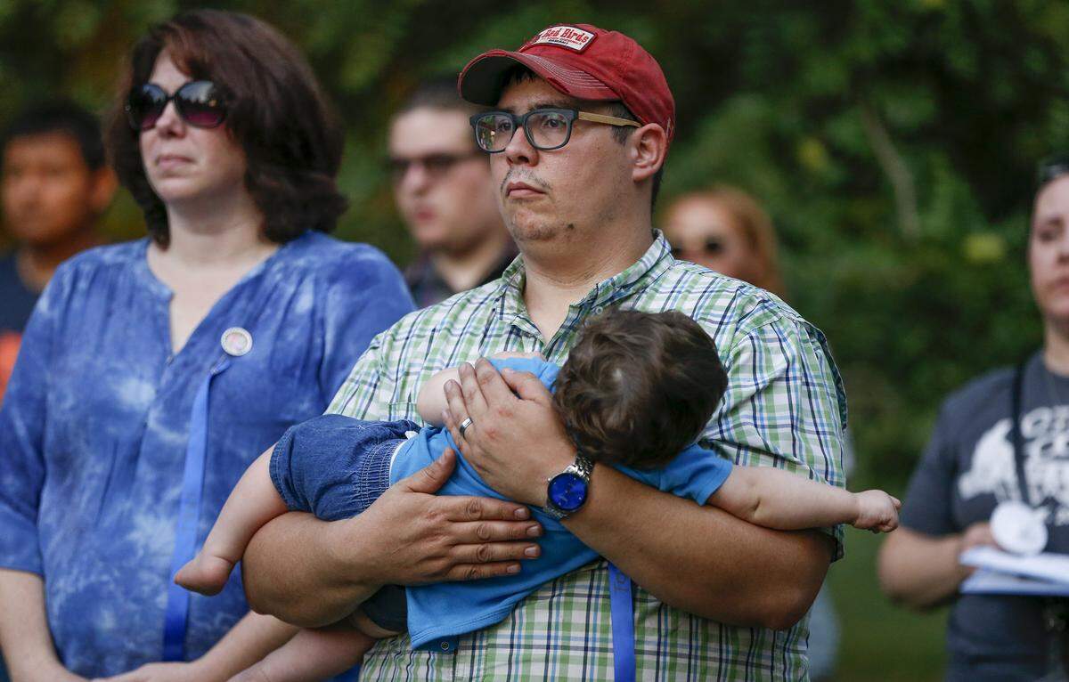 A man holds his son during a candlelight vigil Monday as he listens to the grandparents of Tony Bunn, 2, who was killed by blunt force trauma in May 2018. The boy’s mother and her boyfriend are charged with murder.