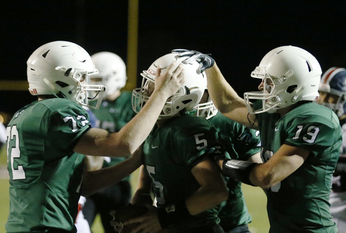 Teammates celebrate with Derby quarterback Hunter Igo after a touchdown against Manhattan in the first half.  (November 16, 2018)
