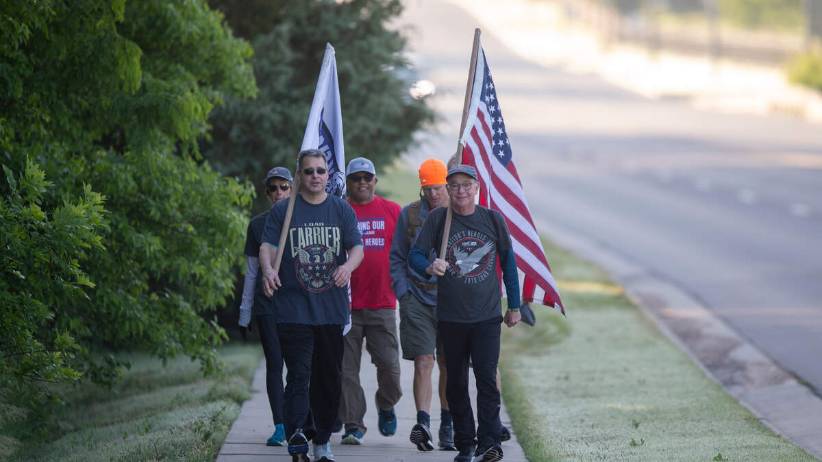A relay team of five people with Carry The Load walk along East 13th Street near 127th Street East early Friday morning. Carry The Load made its way through Wichita as a part of its 20,000-mile national relay to honor and remember our fallen military and first responders. (May 27, 2022)