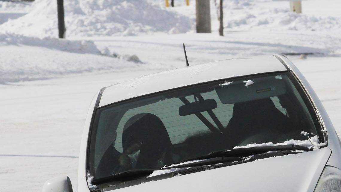 A motorist looks at the damage to his car after he lost control on a snow-packed 21st street near Woodlawn Wednesday afternoon.  No one was injured in the one-car mishap.  (Feb. 5, 2014)