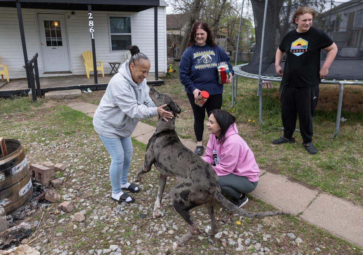 Maria Montoya, left, and Kylee Wallentine, kneeling, play with a Great Dane after delivering dog food to the dog’s owners in Planeview on Tuesday.