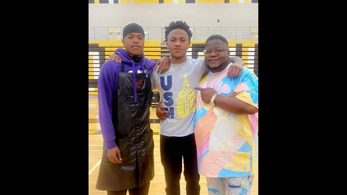Wesley Adkins, center, on signing day, announcing he was going to play basketball at University of Saint Mary in Leavenworth. His cousin, Knowledge McPherson, rushed over from barber school to be there. His uncle, Billy McPherson, came as well.