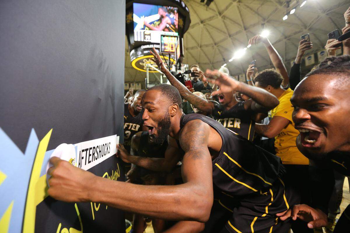 Markis McDuffie places the AfterShocks banner on the tournament bracket wall after they won their second straight regional championship in The Basketball Tournament.