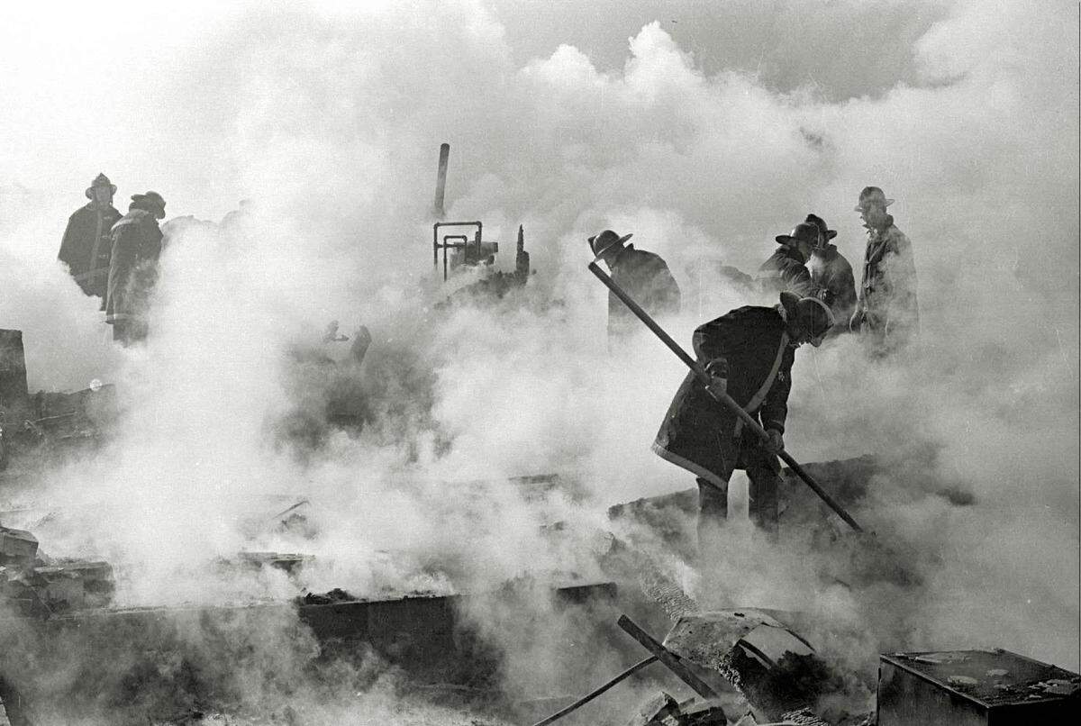In 1965, firefighters sift through the damaged houses and airplane wreckage after a KC-135 tanker jet crashed in a neighborhood near 20th and Piatt in northeast Wichita.