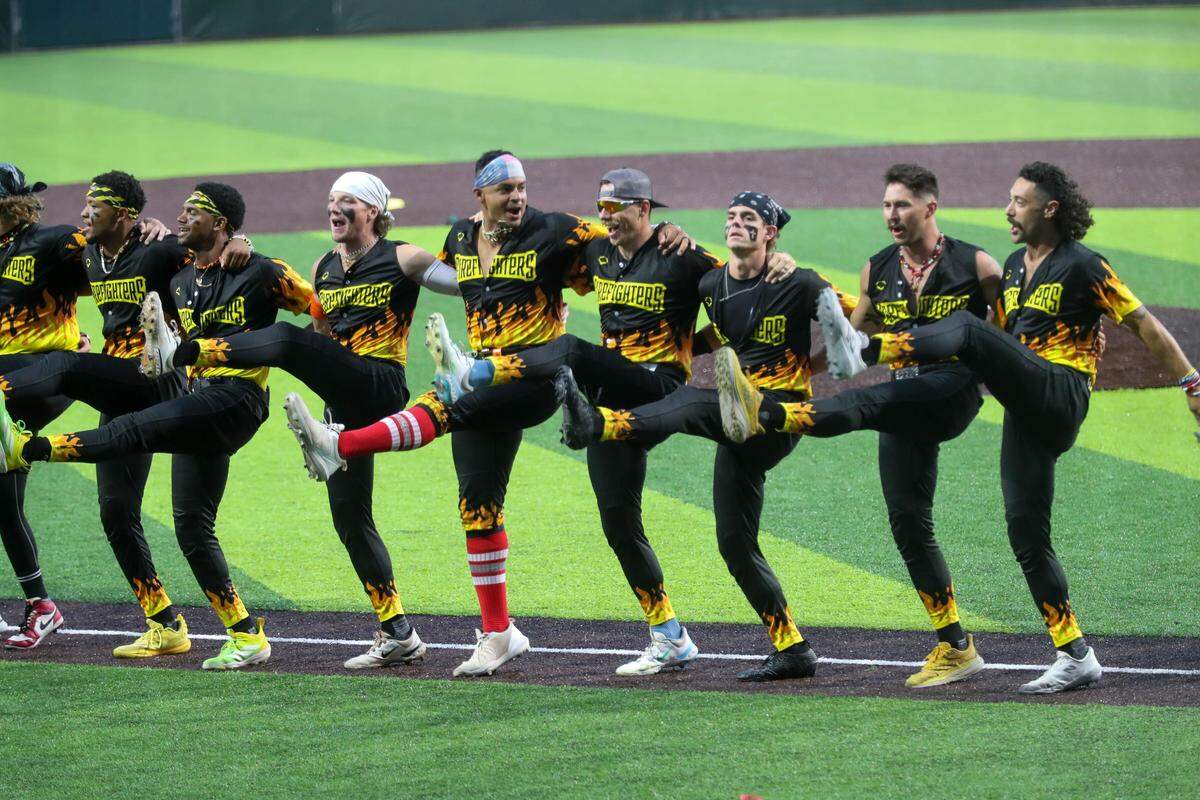 Players from the Firefighters perform a kick line during the first game of the Banana Ball Championship series on Thursday, October 2, 2025 at Historic Grayson Stadium.